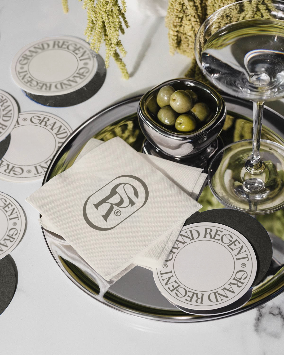 Grand Regent monogram napkins and coasters on a silver tray with olives and a martini glass